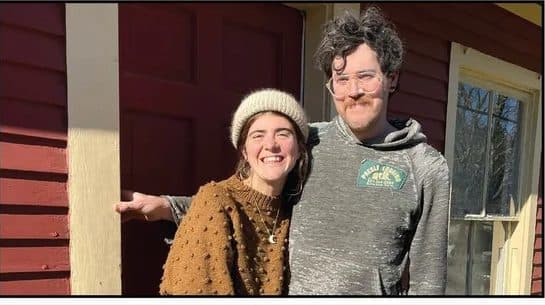 A young couple smiling on the porch of the Little Red House